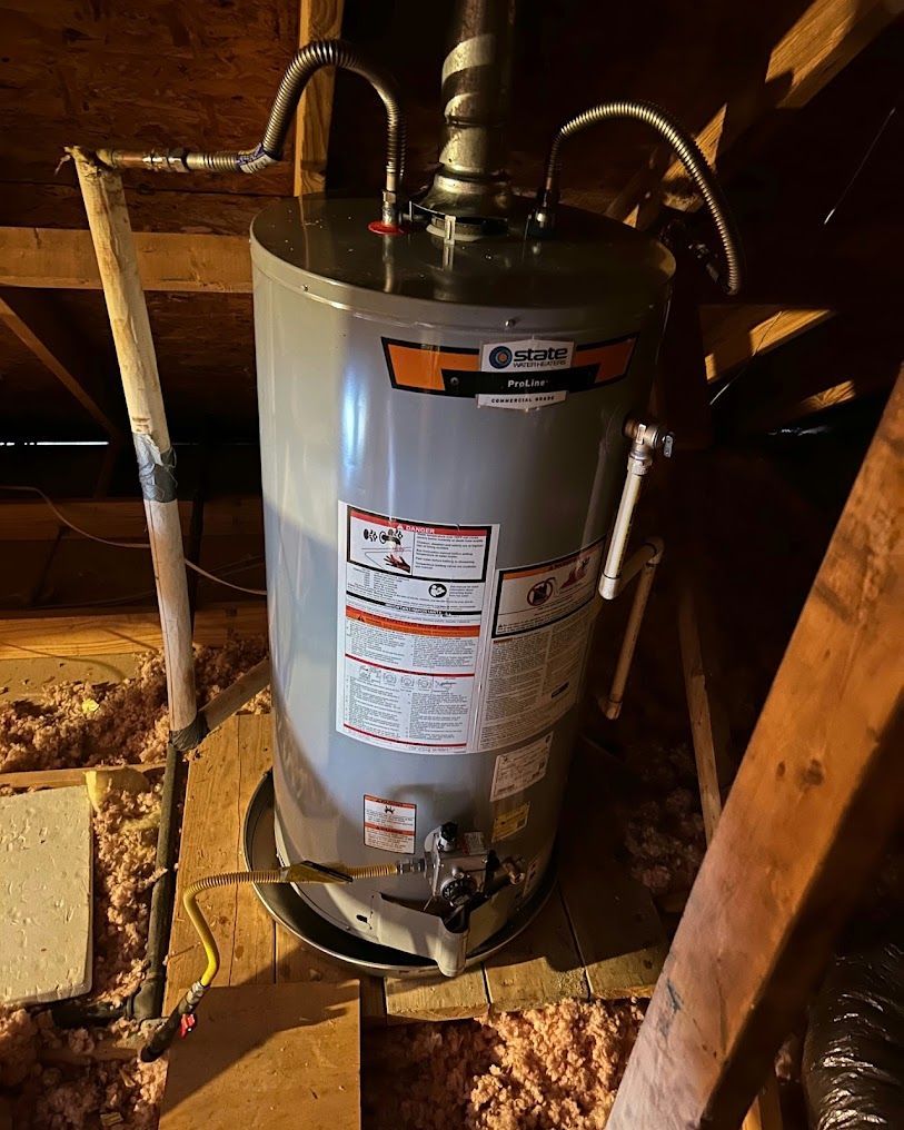 Water heater in a crawlspace, with pipes and labels on a silver tank surrounded by wooden framing.