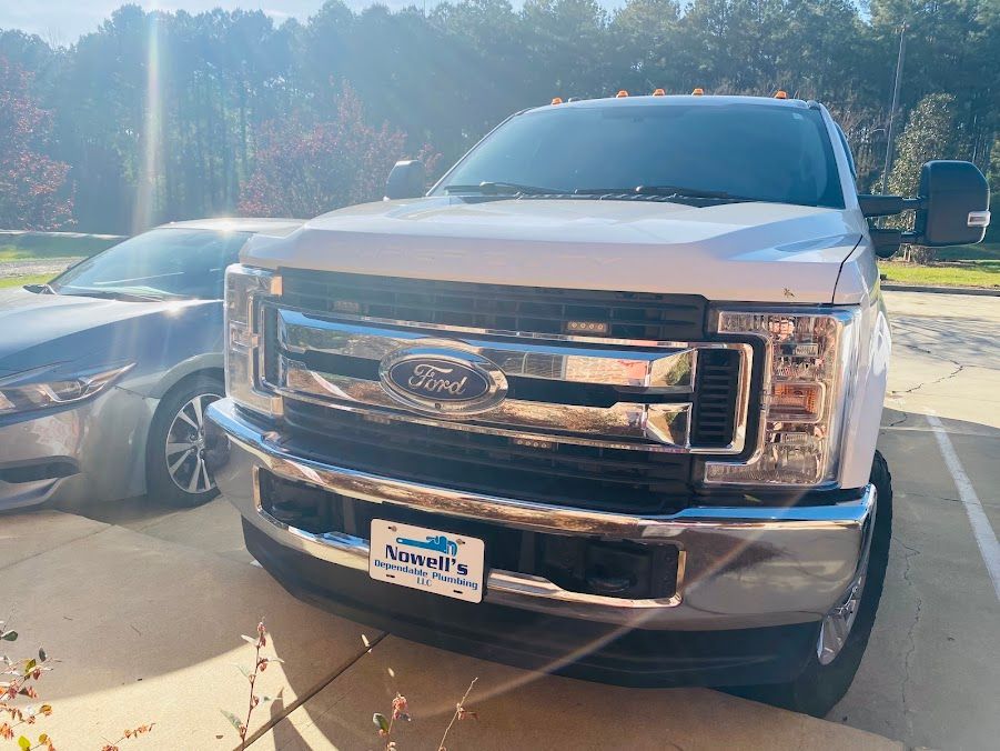 Silver Ford pickup truck parked beside a gray car on a sunny driveway.