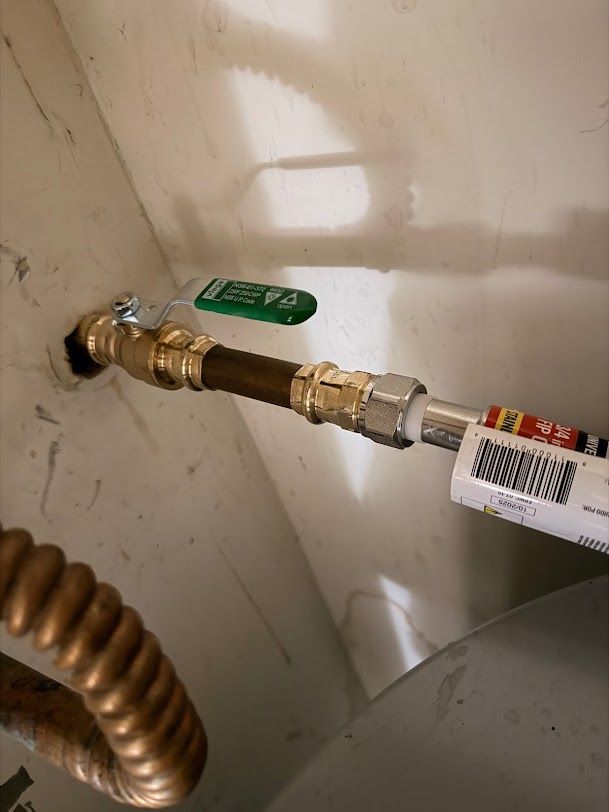 Gas shutoff valve and flexible line inside a utility cabinet, with a green lever handle.