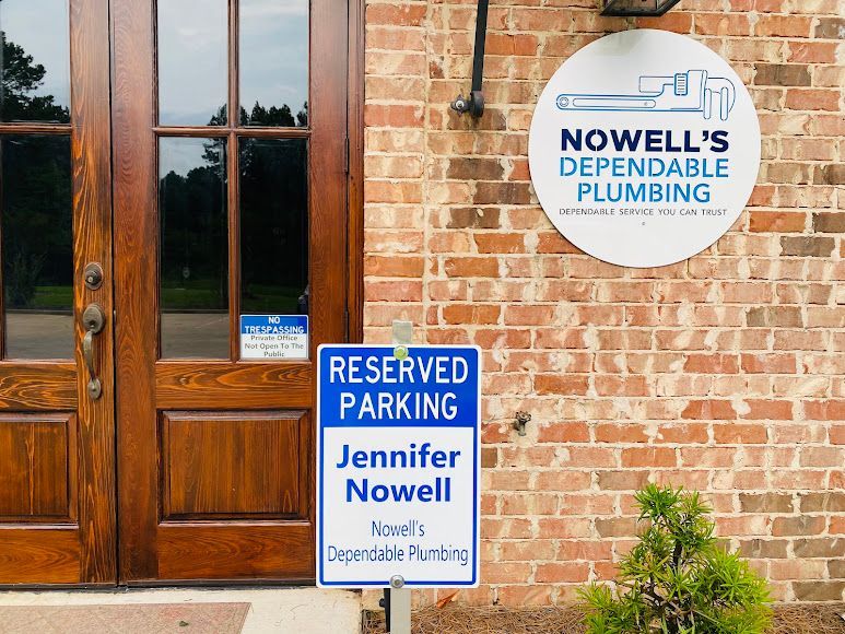 Brick building entrance with reserved parking sign for Jennifer Nowell and Nowell’s Dependable Plumbing sign