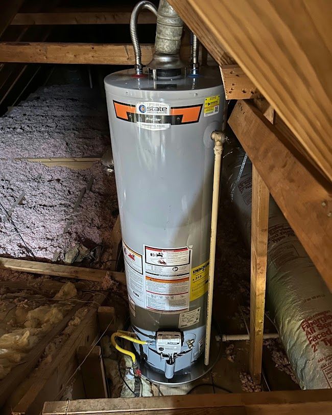 Water heater in an attic crawlspace with exposed ducting and insulation.