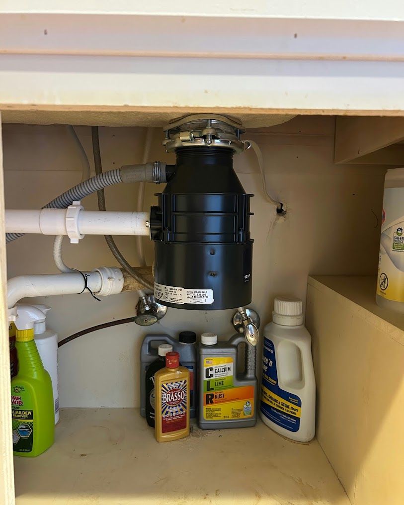 Under-sink cabinet with a garbage disposal, pipes, and cleaning supplies on both sides