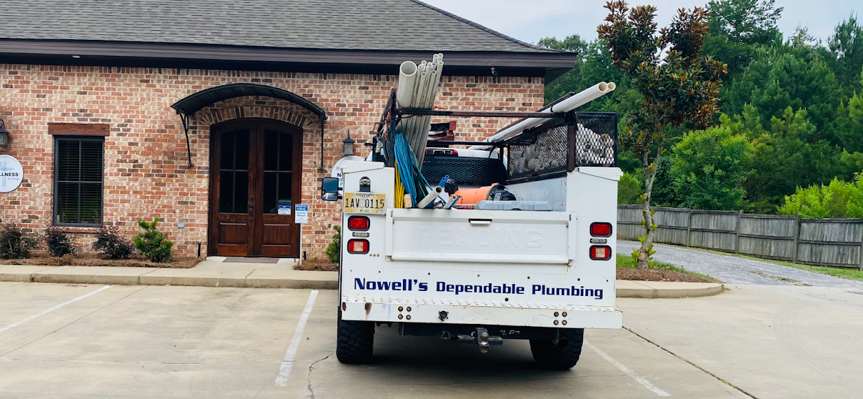 White utility truck parked by a brick house, loaded with debris, in a driveway.