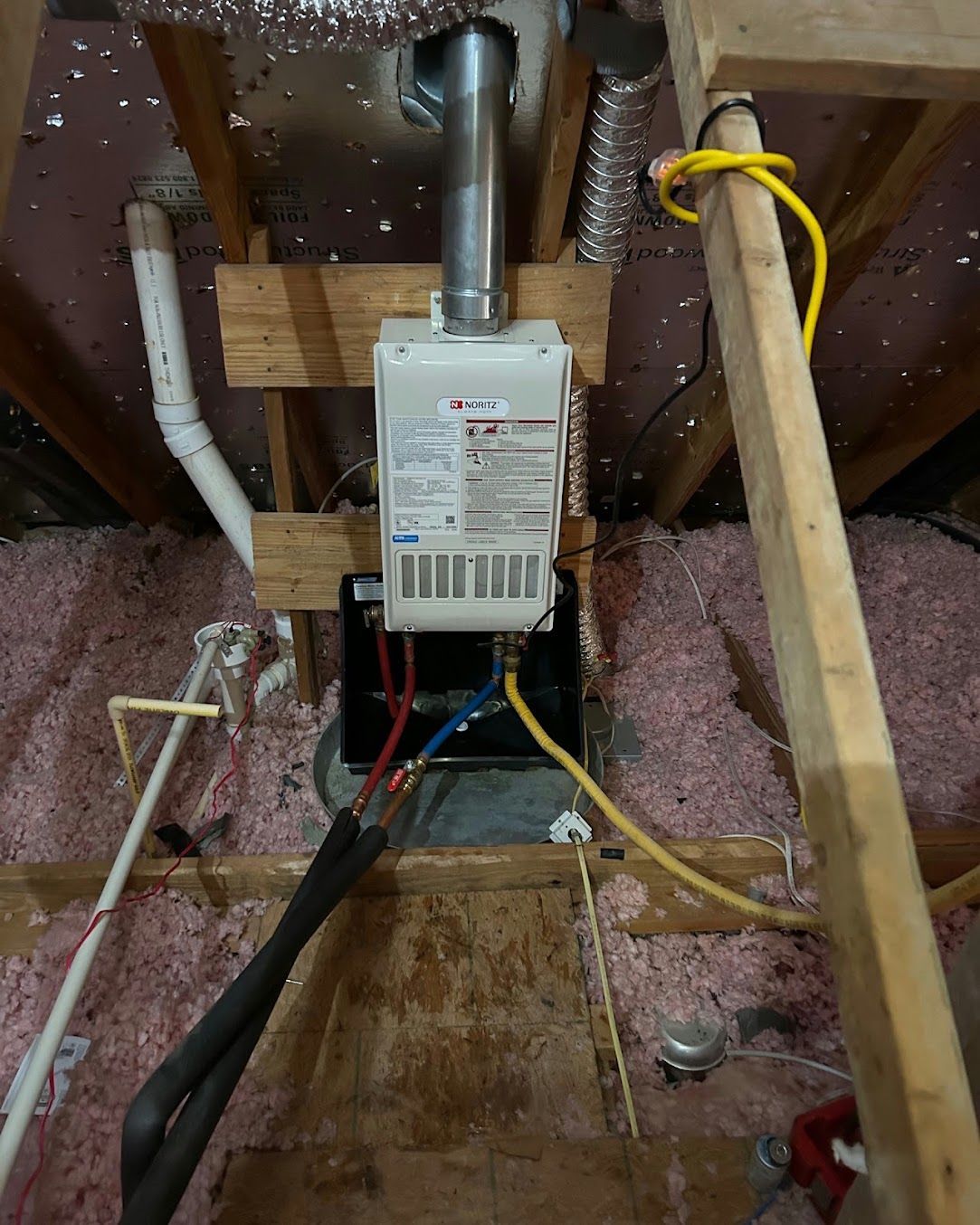 Under-sink electrical box with exposed wiring, a wooden board, and pink insulation around it