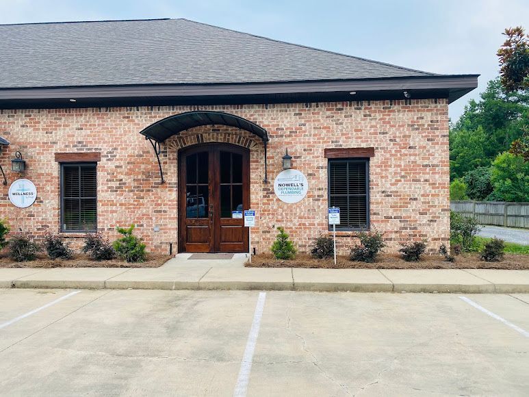 Brick office building with dark roof, wooden double doors, and parking spaces in front