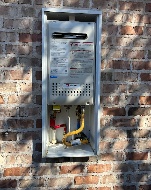 Wall-mounted gas meter and shutoff valves in a brick exterior utility enclosure