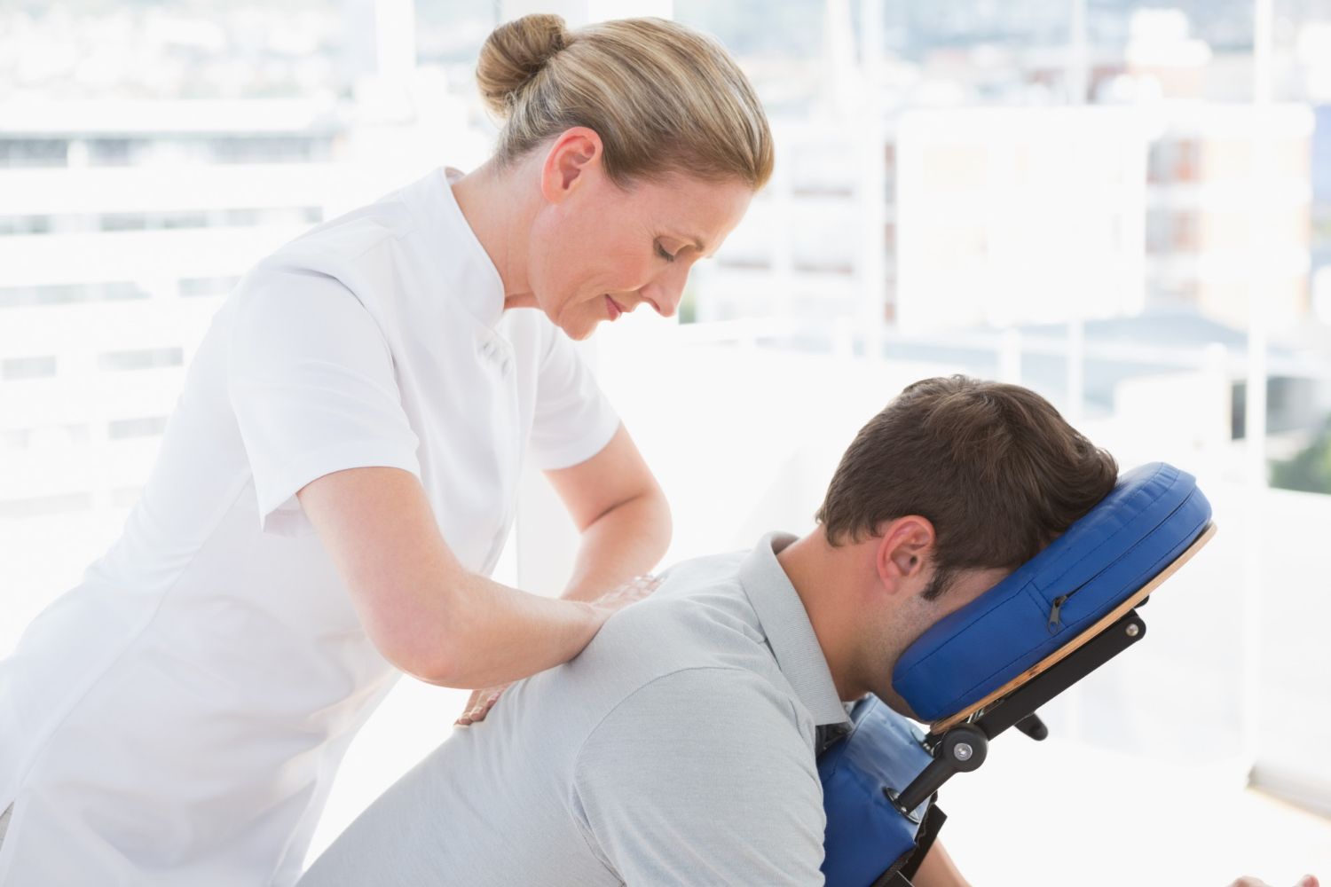 A woman is giving a man a massage in a chair.