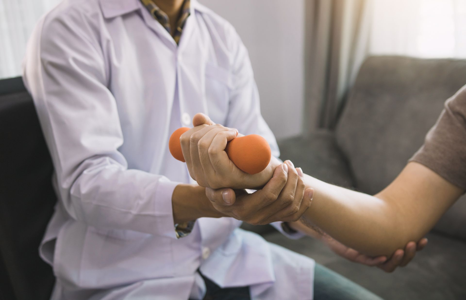 A doctor is helping a patient with a dumbbell.