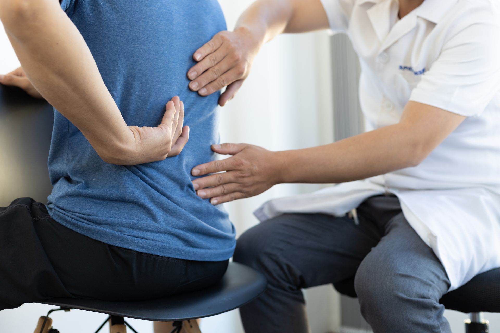 A man is sitting in a chair while a doctor examines his back in Guelph, ON.