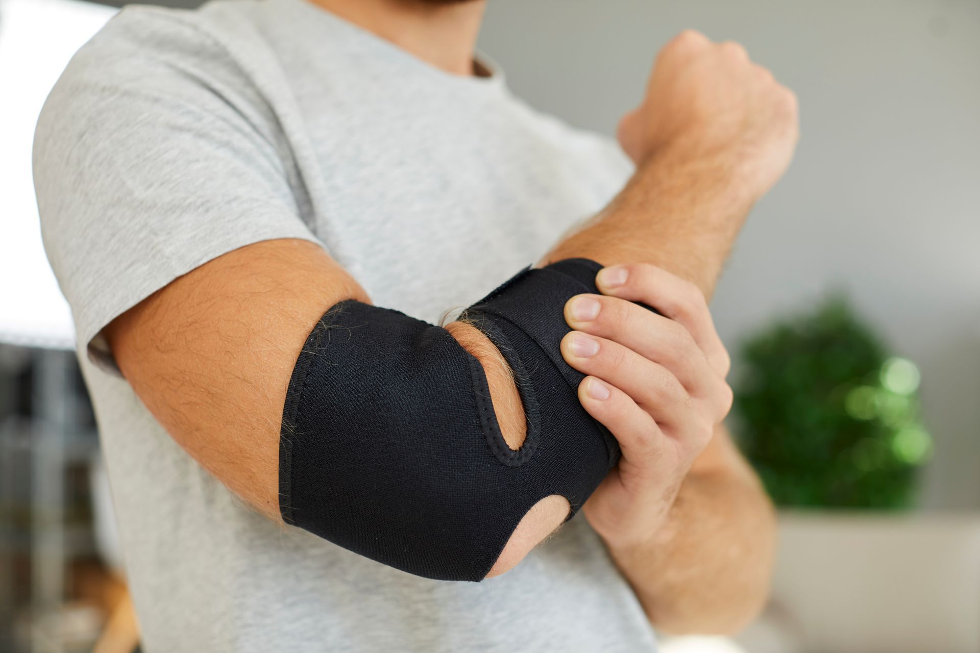 A man is wearing a black elbow brace.