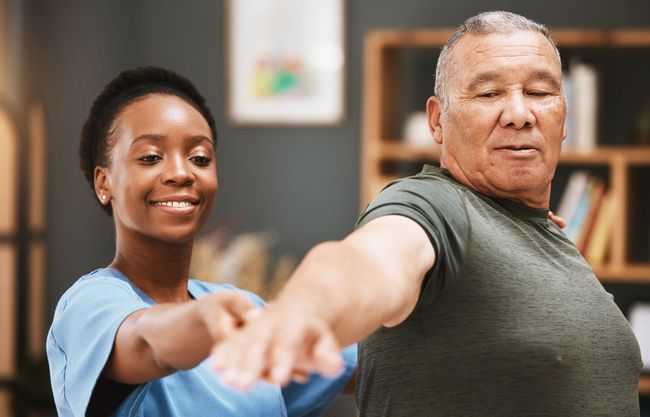A nurse is helping an elderly man stretch his arms in Guelph, ON