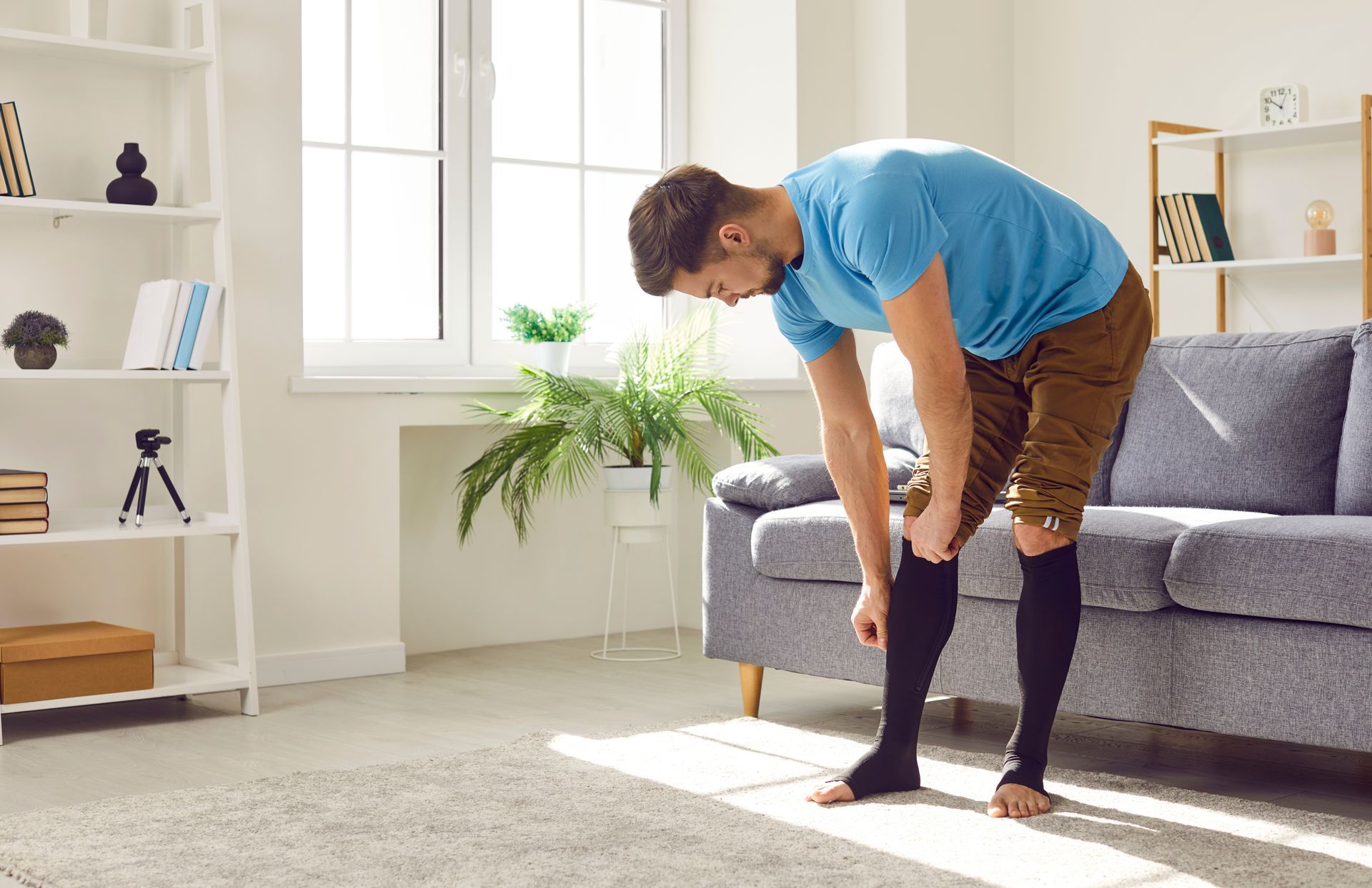 A man is wearing compression socks in a living room in Guelph, ON