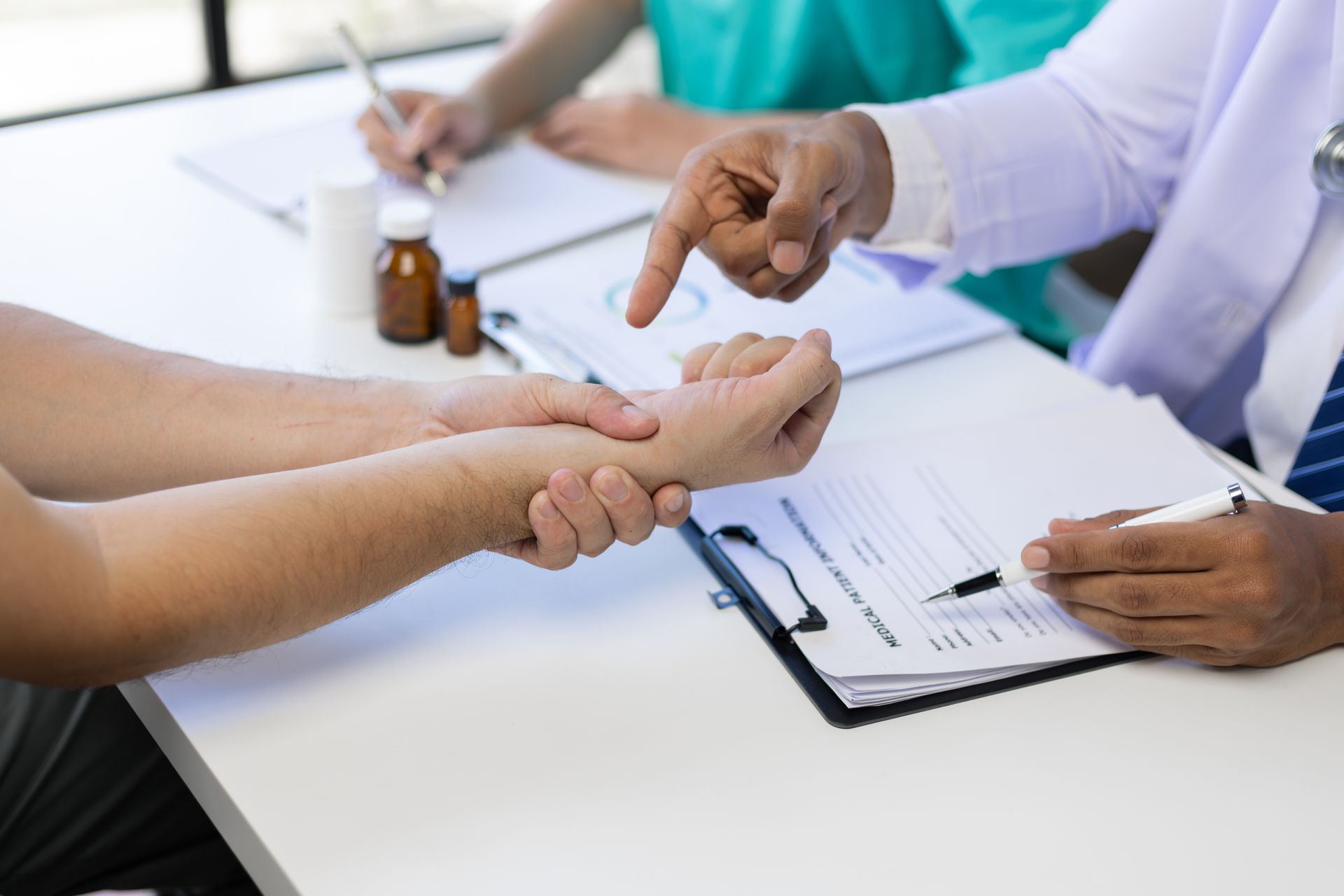 A doctor is examining a patient 's wrist and pointing at it in Guelph, ON