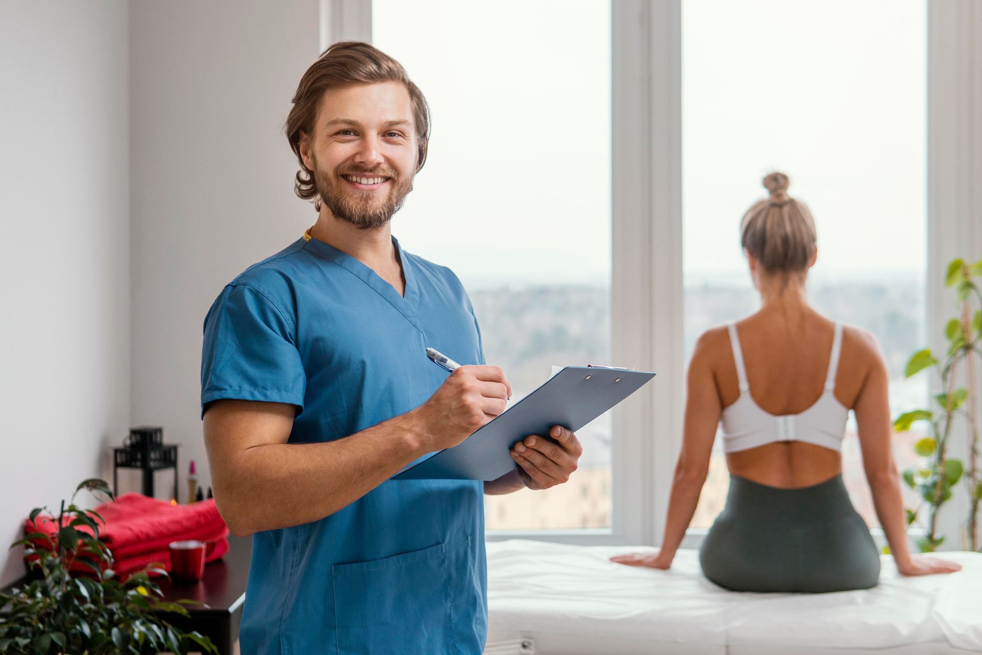 A man is holding a clipboard in front of a woman sitting on a massage table in Guelph, ON