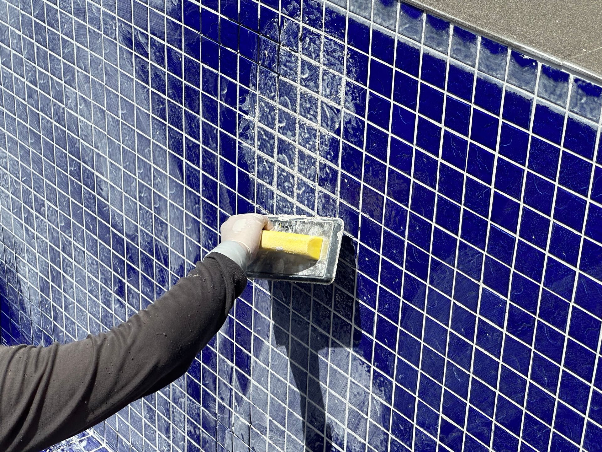 Cleaning a blue tiled wall.