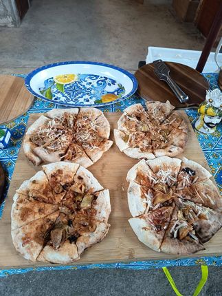 Quattro focacce farcite con carne sfilacciata su un tagliere, con piatti e posate nelle vicinanze.