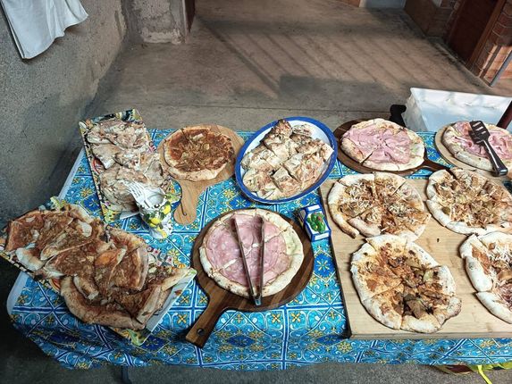 All'interno, su un telo blu steso sul pavimento, si trovano diversi tipi di cibo disposti su piatti e vassoi.
