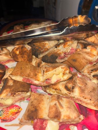 Vassoio con fette di focaccia o pezzi di pizza, con pinze sopra, su un piatto o una tovaglia rosa.