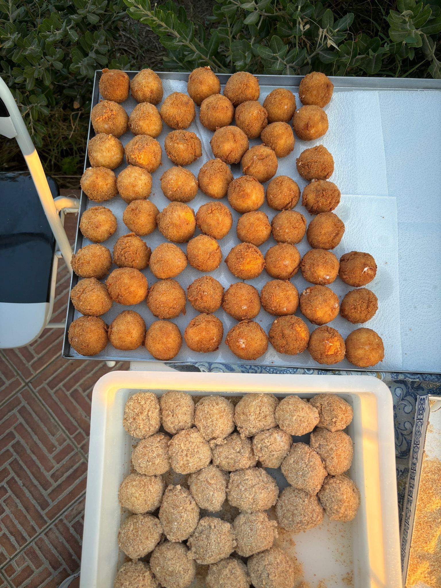 Vassoi di palline di cibo rotonde arancioni e beige disposte all'aperto su un tavolo e in un contenitore