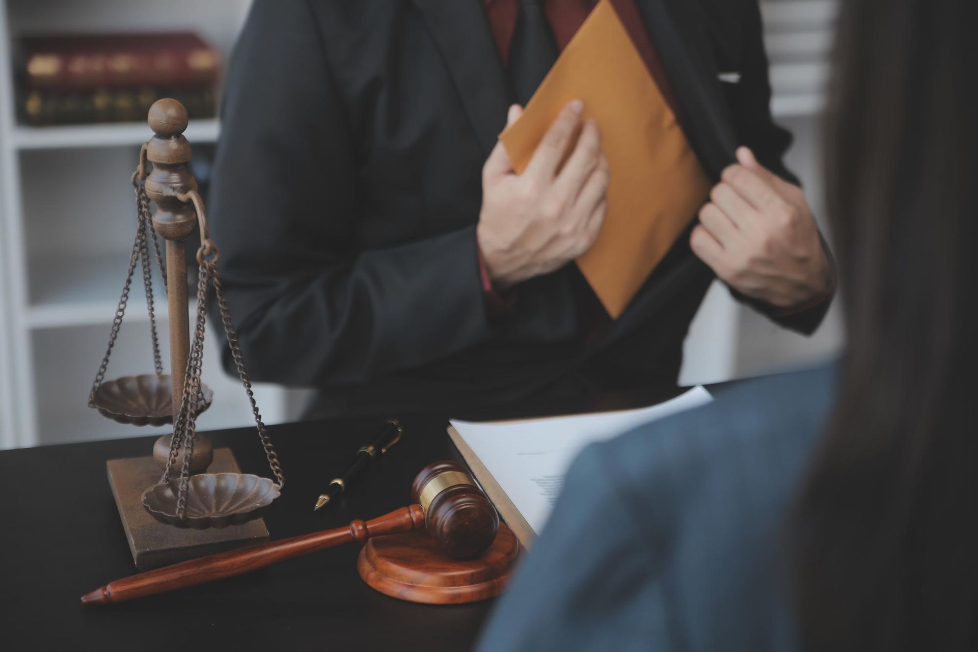 Two people shaking hands over a contract on a desk.