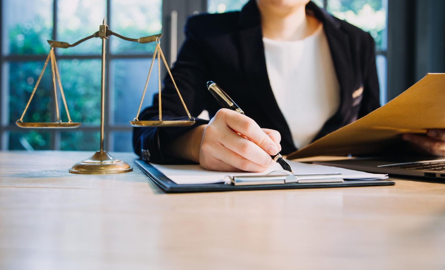 Two people shaking hands over a contract on a desk.
