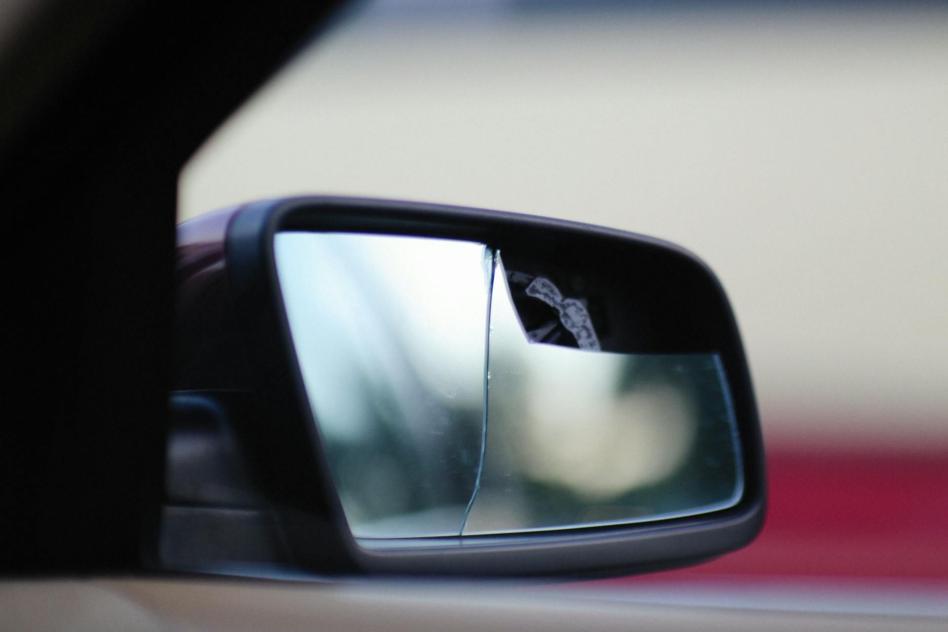 A close-up view of a car's side-view mirror, showing a vertical split between a standard mirror and a wide-angle portion.