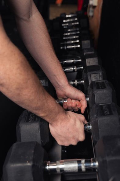 Person adjusting dumbbells on a rack in a gym