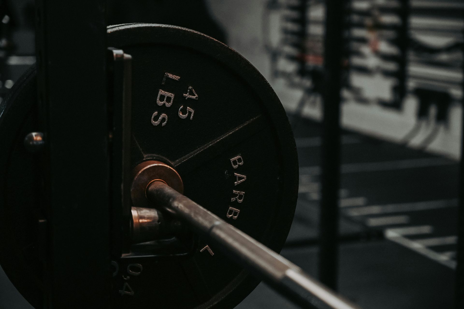 Barbell with weight plates on a gym machine, dark industrial setting