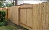 Wooden privacy fence with a gate along a grassy backyard edge