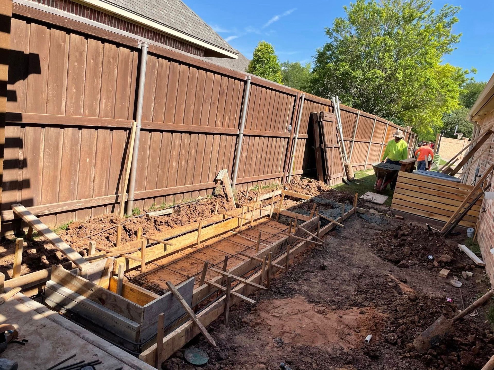 Backyard fence line with wooden formwork and rebar for a concrete footing trench under construction