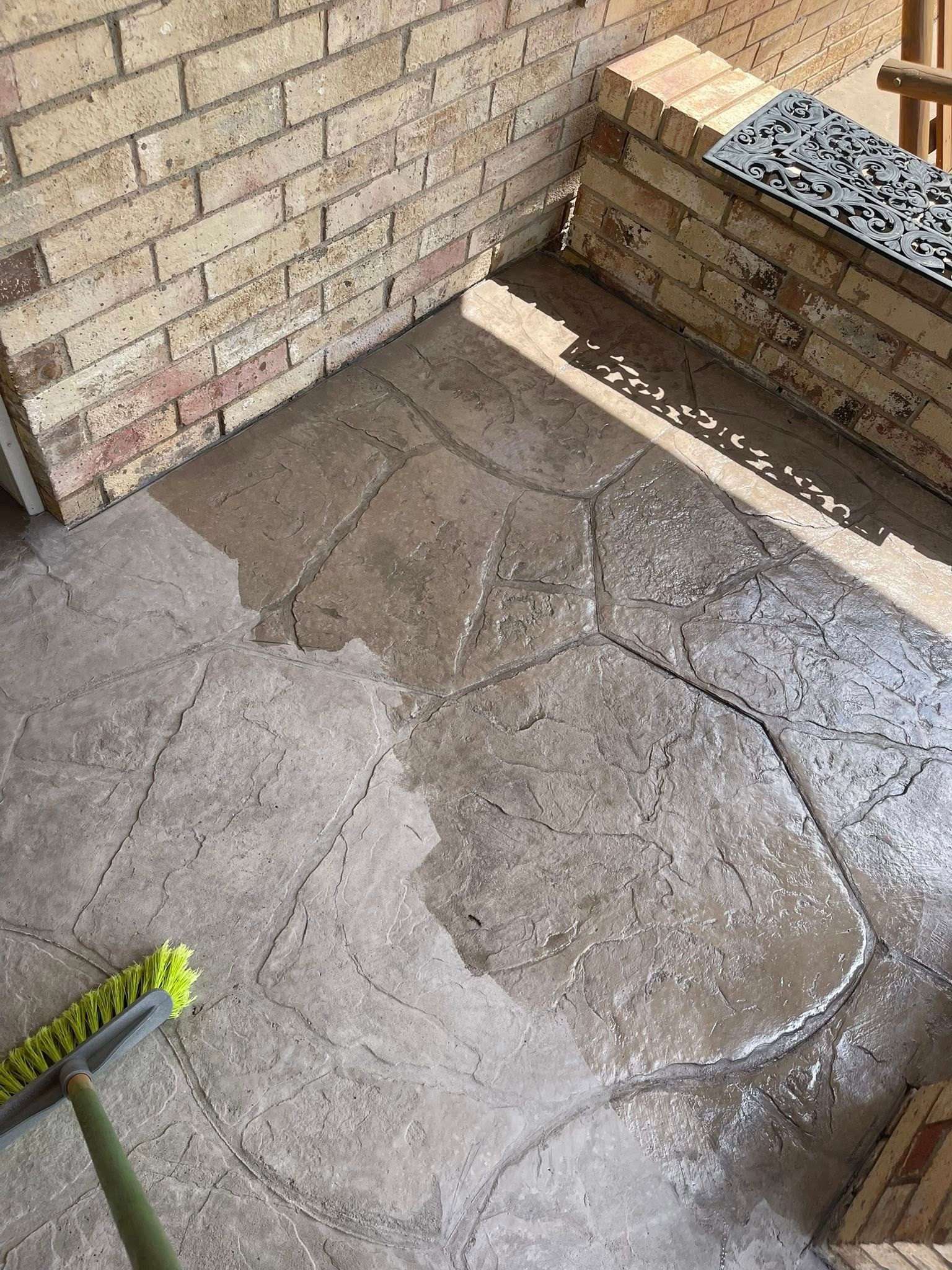 Cracked concrete patio floor beside a brick wall and raised planter bed
