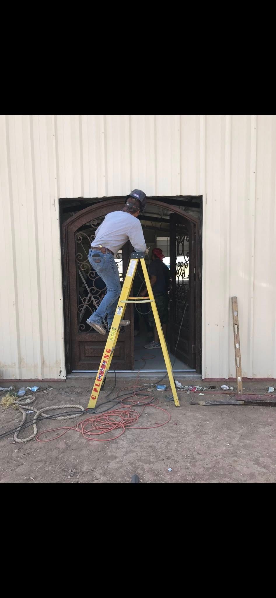 Person on yellow ladder working in a doorway of a beige building