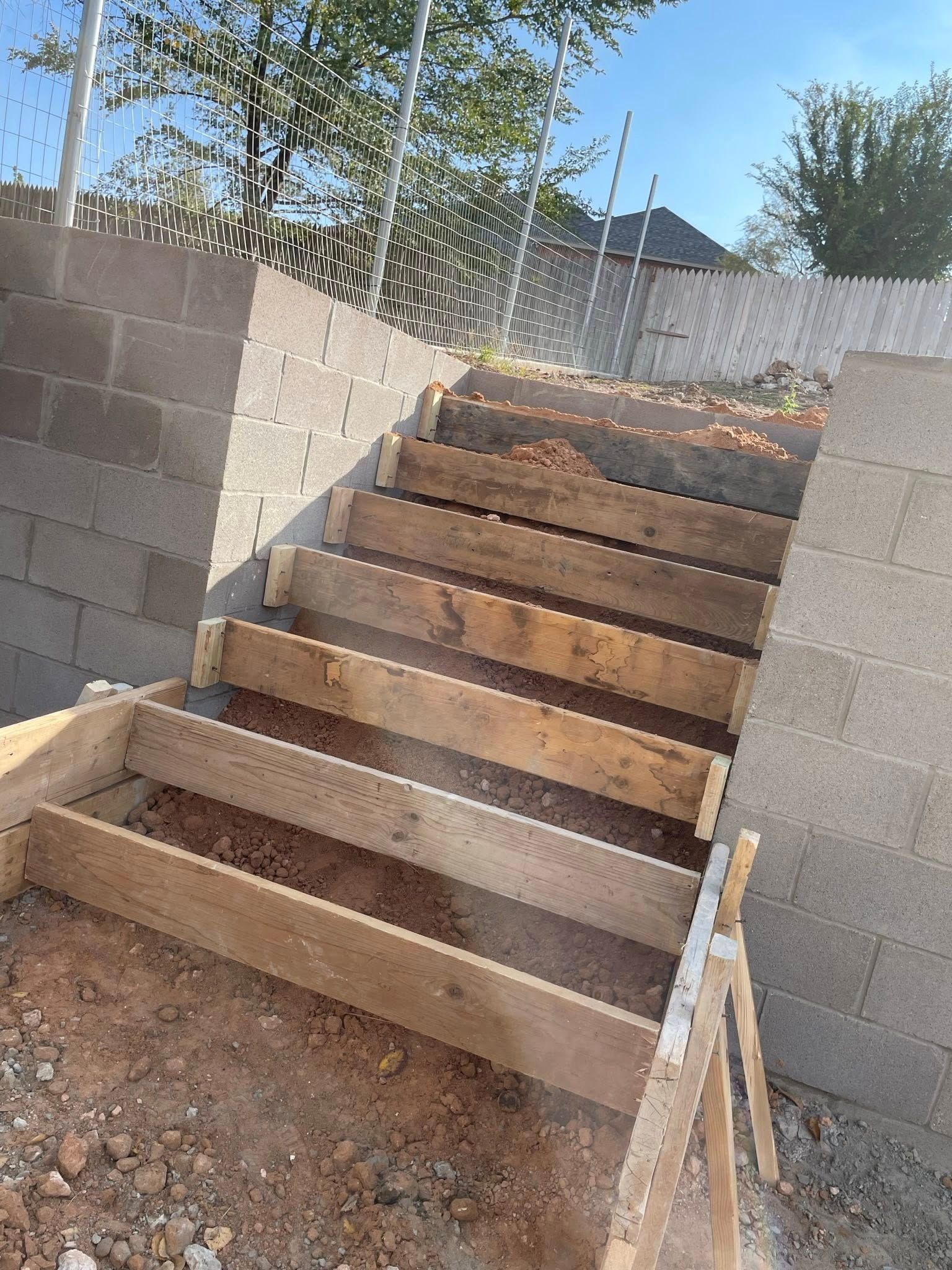 Unfinished outdoor concrete stairway under construction with block walls and dirt around it.