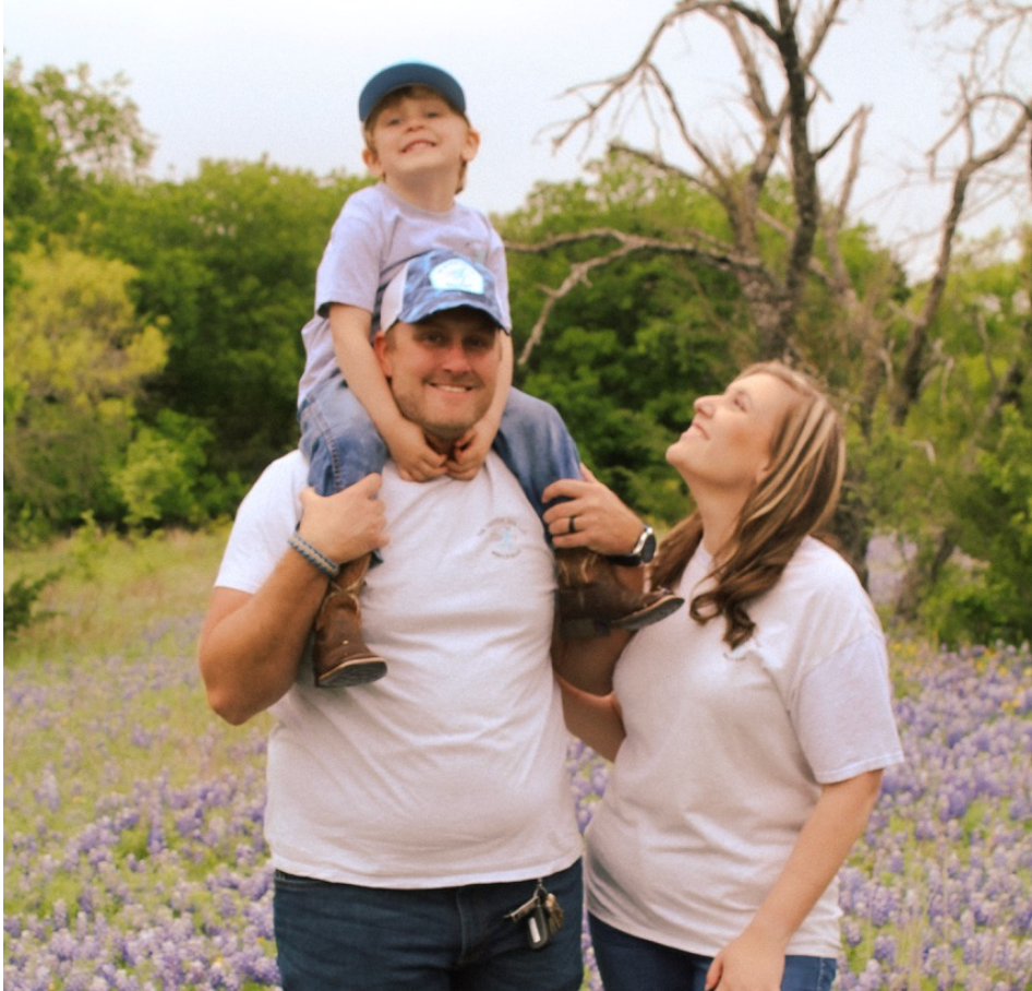 A man is carrying a child on his shoulders in a field