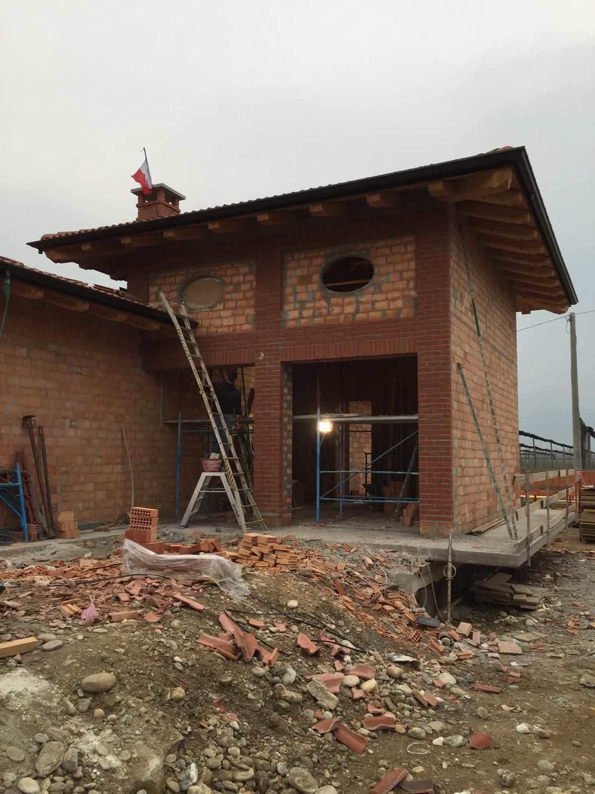 Edificio in costruzione: struttura in mattoni con porta e finestra aperte, tetto parzialmente completato, scala contro il muro.