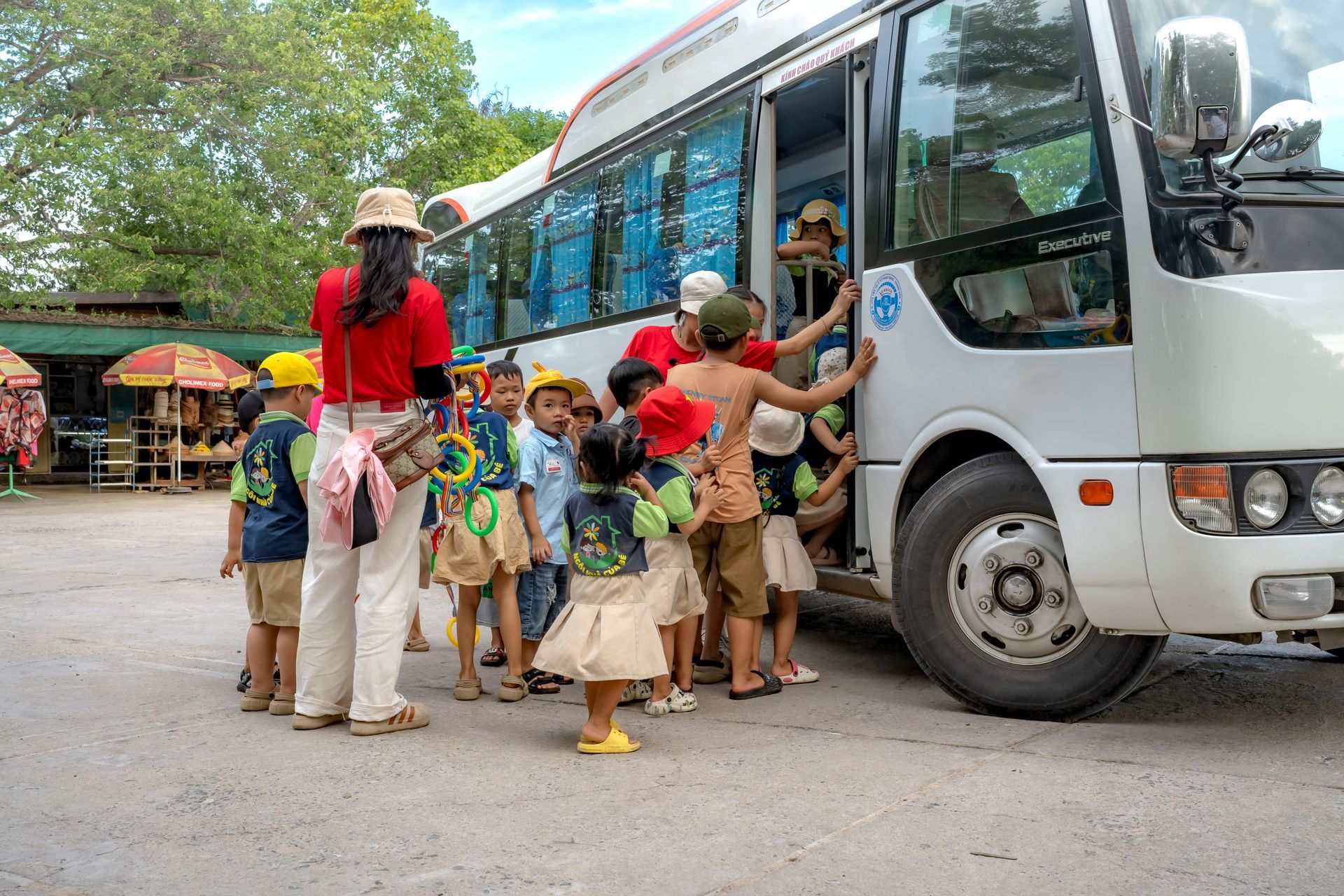 charter bus picking up a group near a SeaWorld-style theme park entrance.