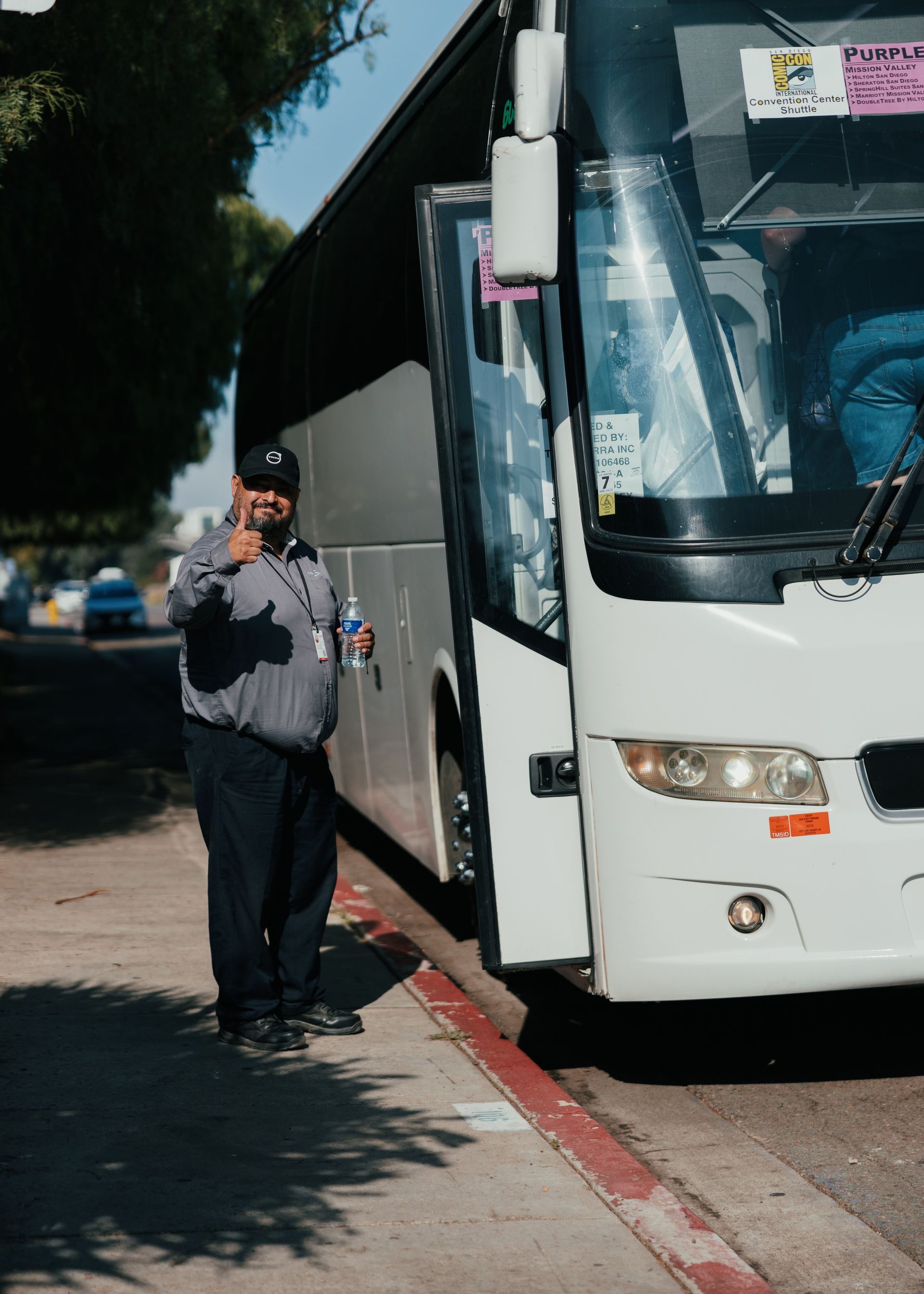 Professional San Diego charter bus driver smiling and greeting the camera before starting a group trip.