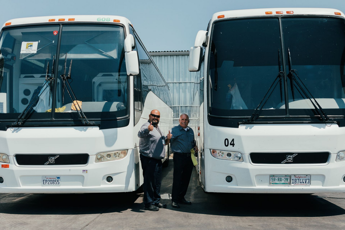 Friendly charter bus drivers posing with bus ready to provide professional transportation services