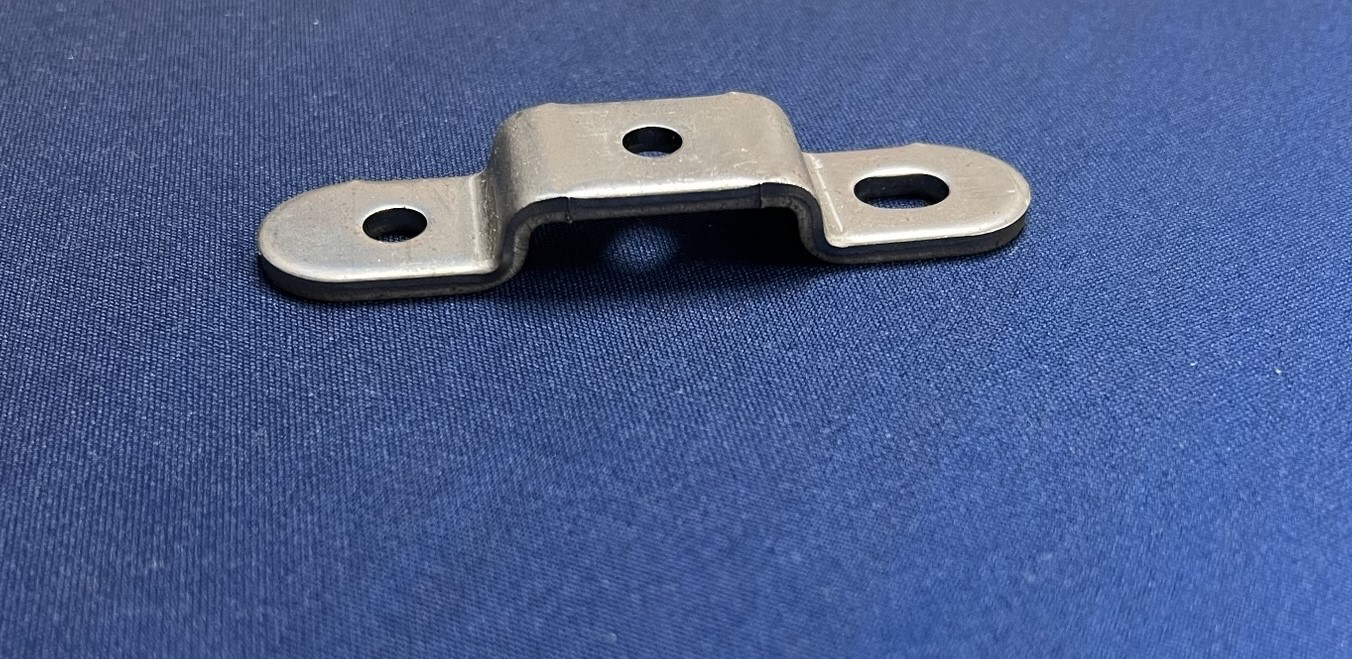 A small metal object is sitting on a blue surface.