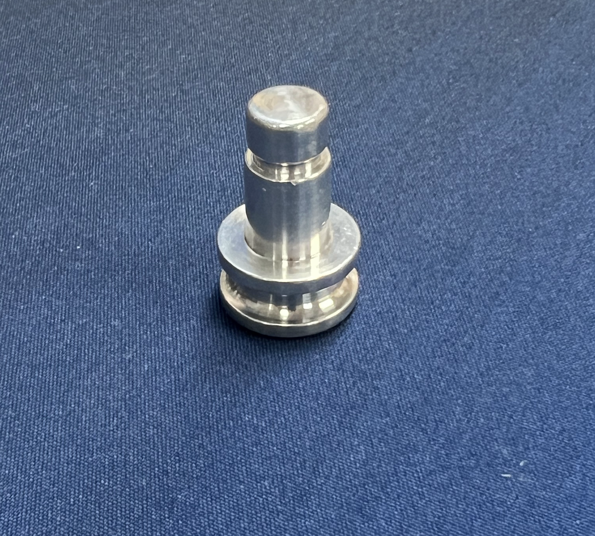 A small metal object is sitting on a blue cloth.