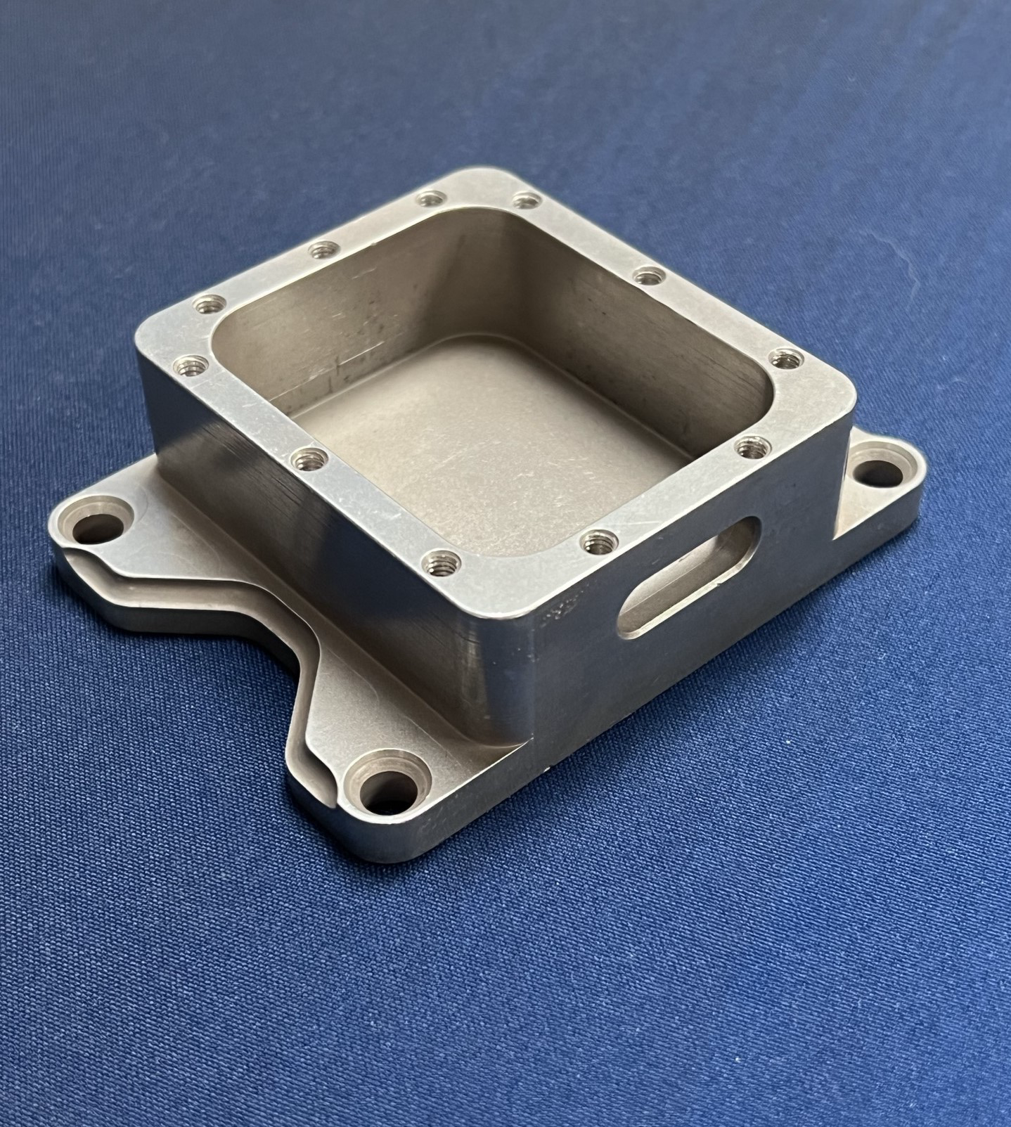 A metal block with holes in it is sitting on a blue surface