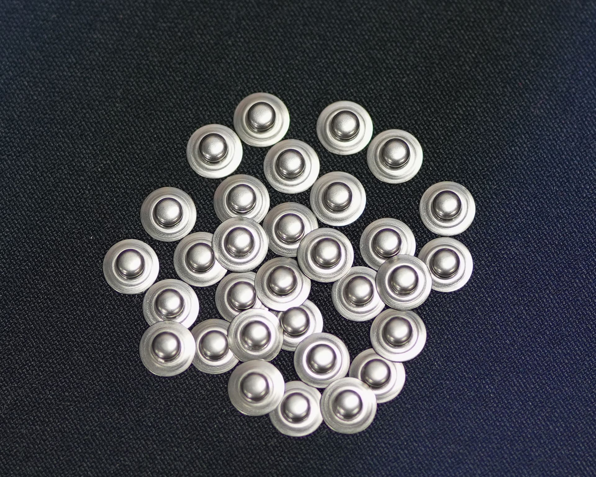 A bunch of silver beads are sitting on top of each other on a blue surface.