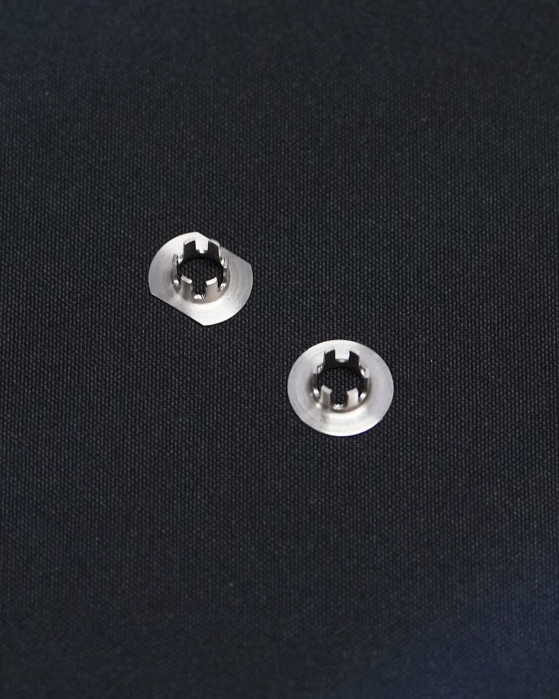 A pair of buttons are sitting on top of a black cloth.
