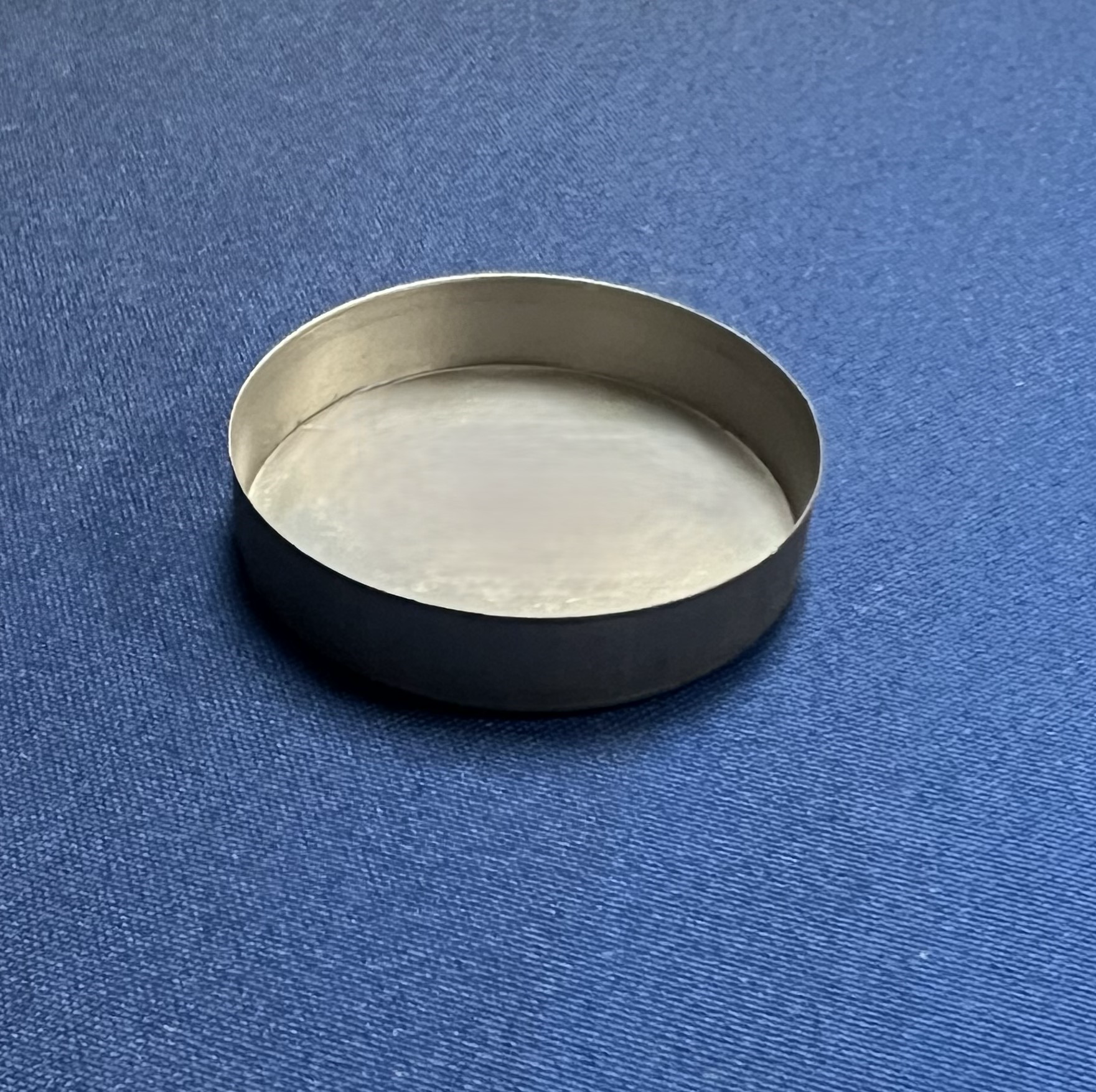 A round metal object is sitting on a blue surface