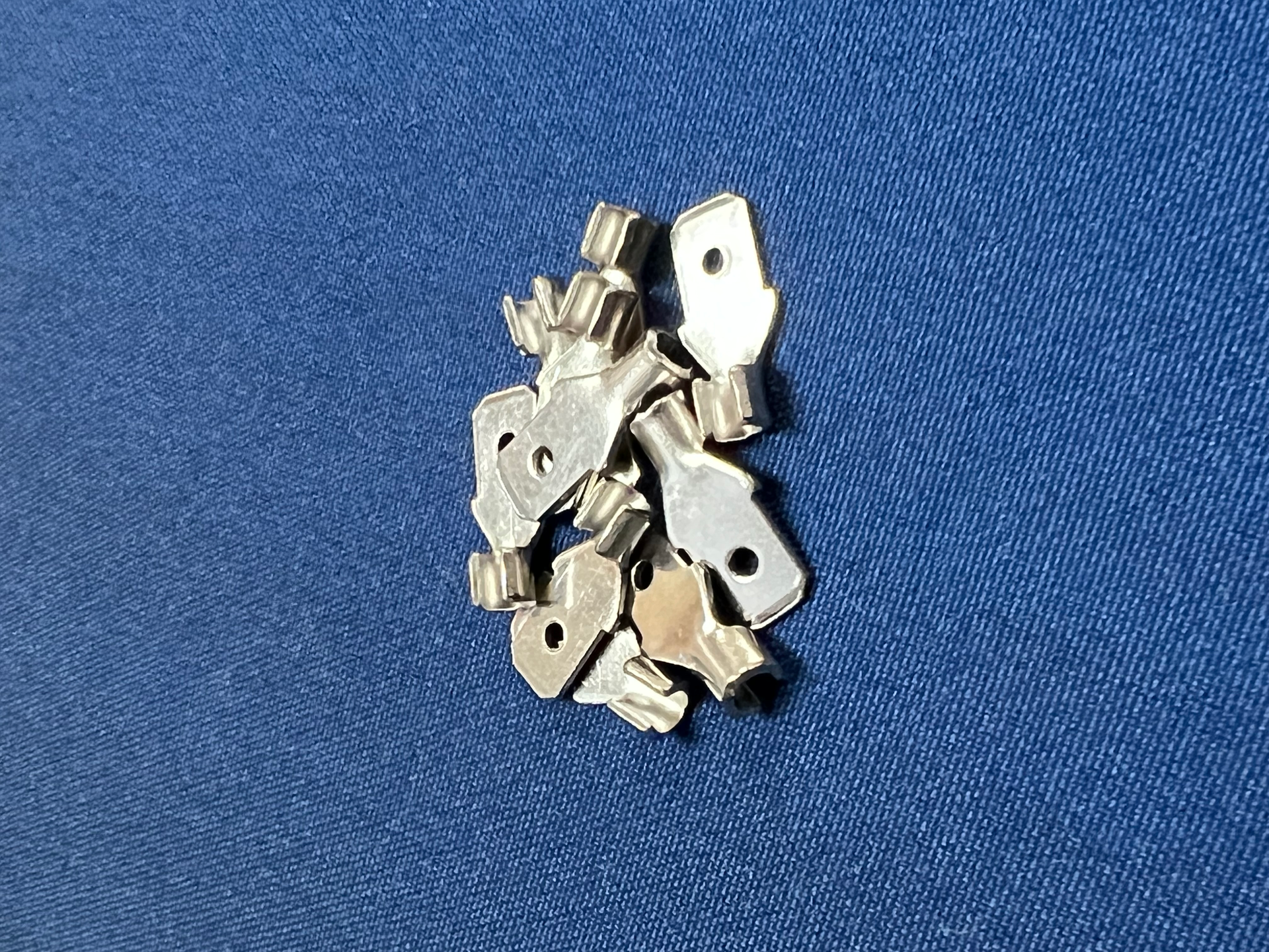 A pile of keys are sitting on a blue surface.