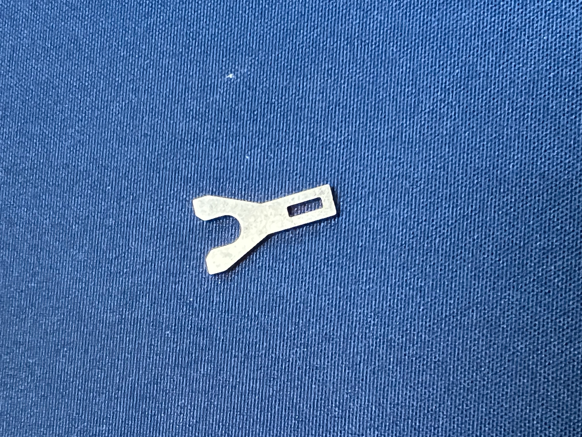 A small metal object is sitting on top of a blue cloth.