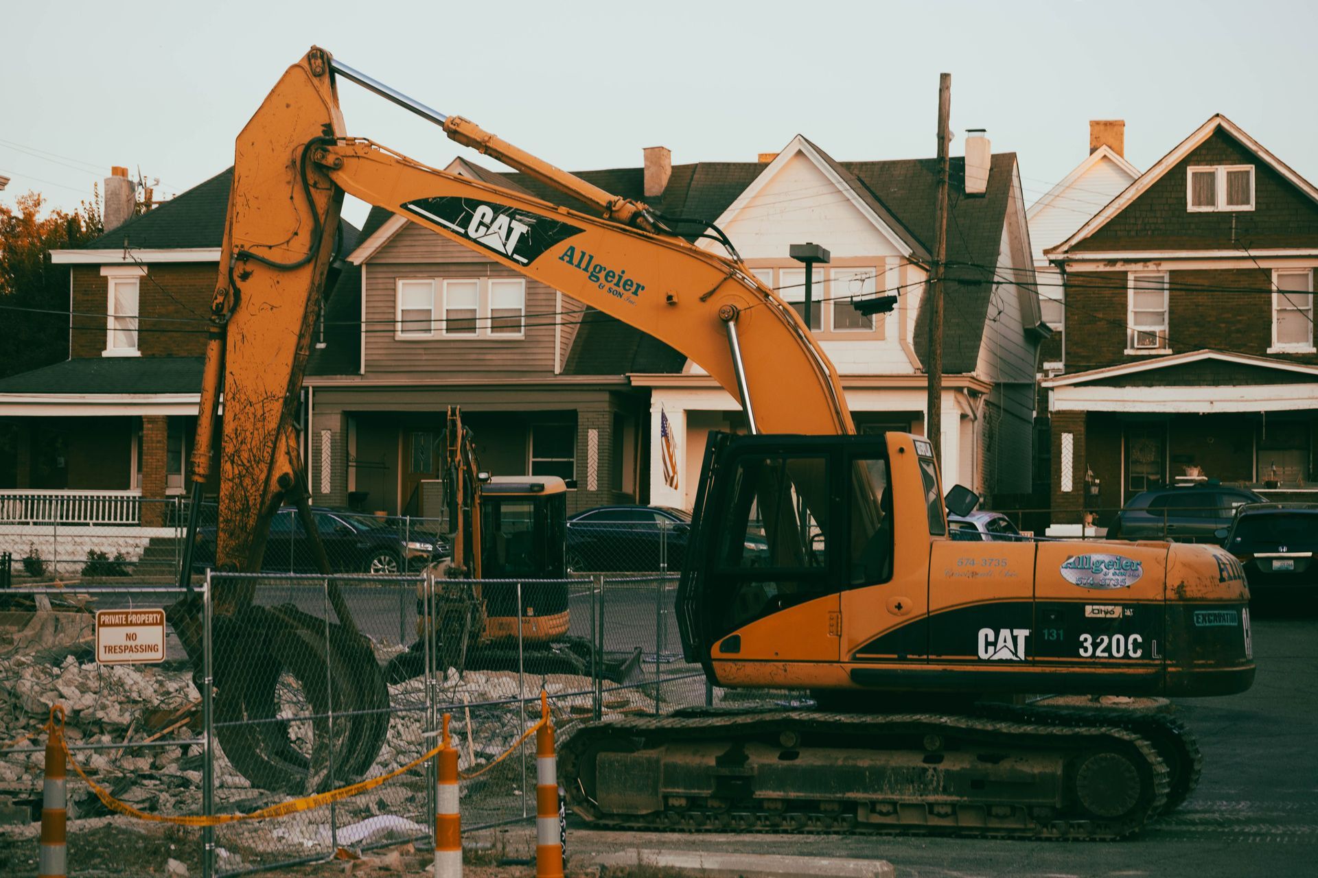 Yellow CAT excavator parked in front of houses during construction work