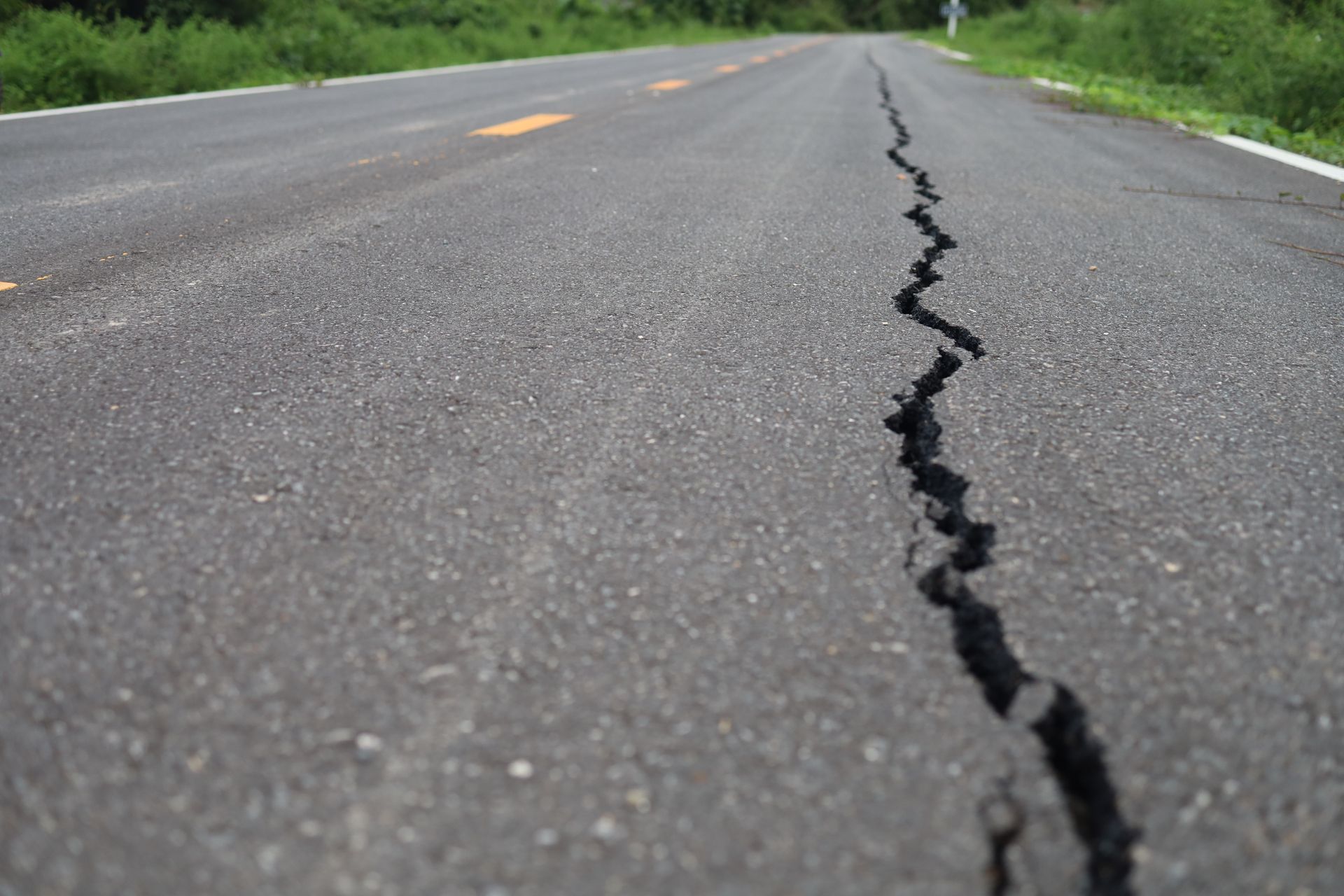 Cracked asphalt road with a jagged fissure running down the center