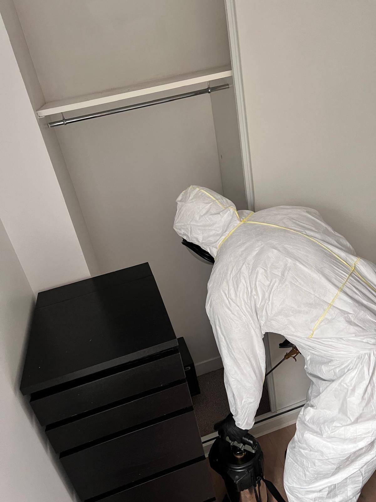 Photo d’un technicien NGAN Eure-et-Loir intervenant dans un logement, en combinaison de protection, avec équipement de pulvérisation — intervention raisonnée contre les puces.