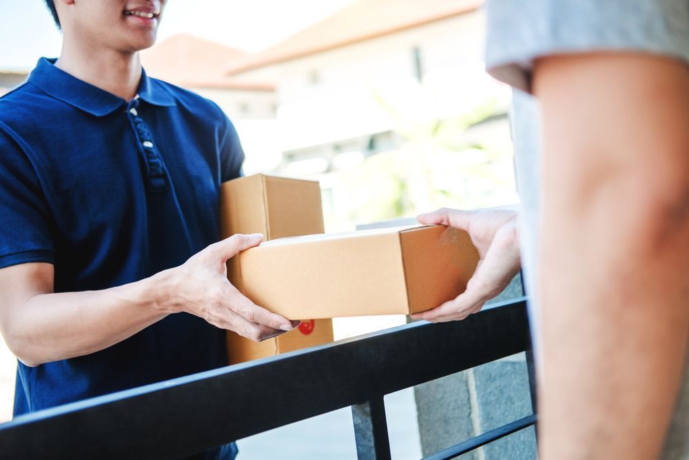 A Delivery Man is Handing a Box to a Woman — Express Couriers Mackay in West Mackay, QLD